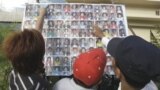 A Cambodian man compares a photo to those of stampede victims at Preah Kossamak Hospital in Phnom Penh, Cambodia, 24 Nov 2010.