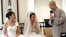 Huang Mei-yu (kiri) dan pasangannya You Ya-ting disambut oleh Biksuni Shih Chao-hui sebelum upacara pernikahan sebagai pasangan lesbian pertama yang dinikahkan dalam pemberkatan Budha di Taoyuan, Taiwan (11/8).