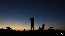 FILE - Tourists photograph the sunset at the summit of Cadillac Mountain in Acadia National Park near Bar Harbor, Maine, USA, Oct. 2, 2014.