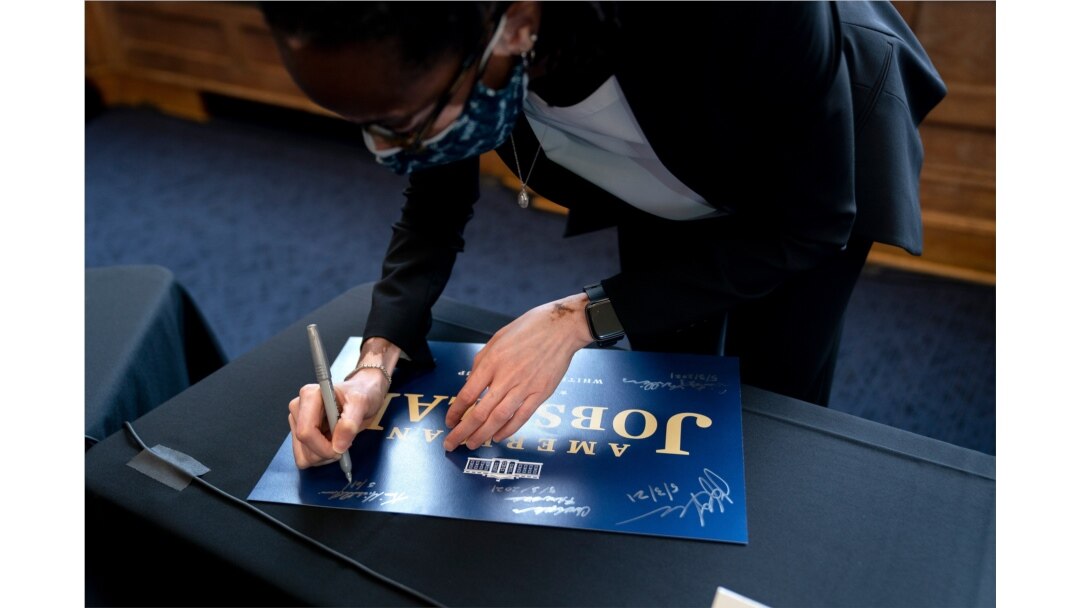 FILE - Kim Lewis, an associate dean at Howard University in Washington, autographs an American Jobs Plan sign after participating with Energy Secretary Jennifer Granholm in a discussion at the university, May 3, 2021.