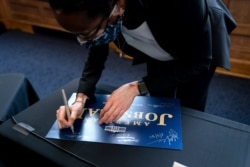 FILE - Kim Lewis, an associate dean at Howard University in Washington, autographs an American Jobs Plan sign after participating with Energy Secretary Jennifer Granholm in a discussion at the university, May 3, 2021.