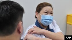 Foto Kementerian Komunikasi dan Informasi Singapura menunjukkan vaksin virus corona COVID-19 diberikan kepada staf perawat senior Sarah Lim (kanan) saat Singapura memulai latihan vaksinasi, 30 Desember 2020. (Foto: AFP)