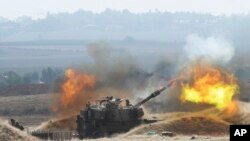 FILE — An Israeli mobile artillery unit firing a shell from towards the Gaza Strip, in a position a near the border between the two regions, Oct. 11, 2023.