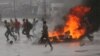 People run at a protest as barricades burn during rainfall in Harare