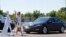 FILE - A pedestrian crosses in front of a vehicle as part of a demonstration at the Mcity test facility at the University of Michigan in Ann Arbor, July 20, 2016. Automakers say cars that wirelessly talk to each other hold the potential to dramatically reduce traffic deaths.