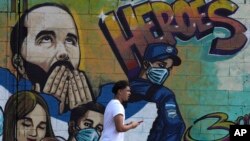 ARCHIVO - Un peatón pasa junto a un mural dedicado a los héroes que presenta al presidente Nayib Bukele en el barrio Soyapango de San Salvador, El Salvador, el 28 de febrero de 2023.