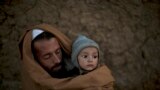 Pakistani Ibrahim Mohammed, 42, who was displaced with his family from Pakistan&#39;s tribal region of Mohmand Agency due to fighting between the Taliban and the army, wraps himself and his son Mashal, 1, with a shawl to avoid the evening cold, while sitting in front of his home in a poor neighborhood on the outskirts of Islamabad.