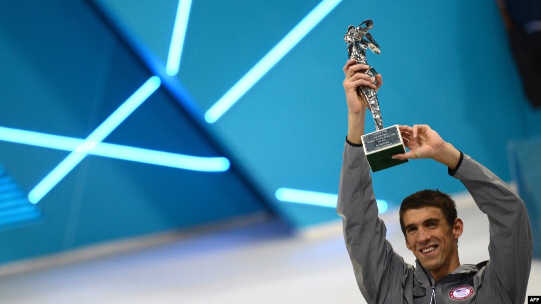 Perenang AS, Michael Phelps mengangkat piala Atlet Terbaik Olimpiade Sepanjang Masa yang diperolehnya setelah memenangkan medali emas dalam nomor final pertandingan renang putra 4x100m medley di Olimpiade London 2012 (4/8).