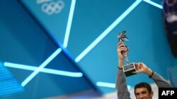US swimmer Michael Phelps poses after receiving the trophy of the greatest olympic athlete of all time after winning gold in the men's 4x100m medley relay final during the swimming event at the London 2012 Olympic Games on August 4, 2012 in London. 