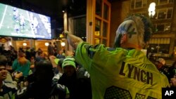 Penggemar Seattle Seahawks, Dustin Pittis menunjuk ke layar televisi (1/2) saat menonton acara Super Bowl XLIX di sebuah bar di Seattle, Washington. (AP/Ted S. Warren)