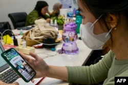 (FILES) Gambar yang diambil pada 4 April 2023 ini memperlihatkan seorang wanita sedang menonton live streaming TikTok yang menawarkan merchandise untuk dijual di Jakarta. (BAY ISMOYO / AFP)