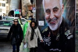 FILE - Women walk past a banner of Iranian military commaner Qassem Soleimani, who was killed in Iraq in a U.S. drone attack, in Tajrish square in northern Tehran, Iran, Jan. 9, 2020.