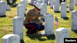 FILE - A female U.S. Marine touches the grave of a friend at Arlington National Cemetery in Virginia. The Veterans Day holiday dates back to 1919.