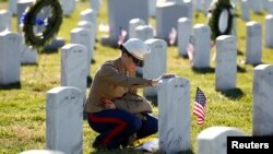 Seorang anggota marinir AS memberikan penghormatan dengan menyentuh batu nisan pada makam rekannya yang dimakamkan di Taman Makam Pahlawan di Arlington, Virginia (Foto: dok).