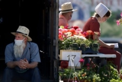 Vendors wait for customers at a drive-through farmers market, May 2, 2020, in Overland Park, Kan. The market moved from its usual home to a sprawling parking lot, allowing people to shop from their cars as a measure to stem the spread of COVID-19.