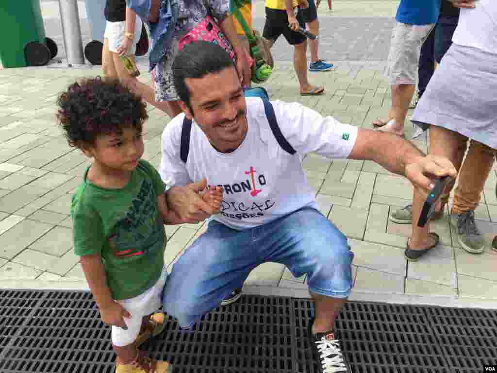 A man and a child document their day with a selfie at the Olympic Games in Rio de Janeiro, Brazil, Aug. 8, 2016. (P. Brewer/VOA)