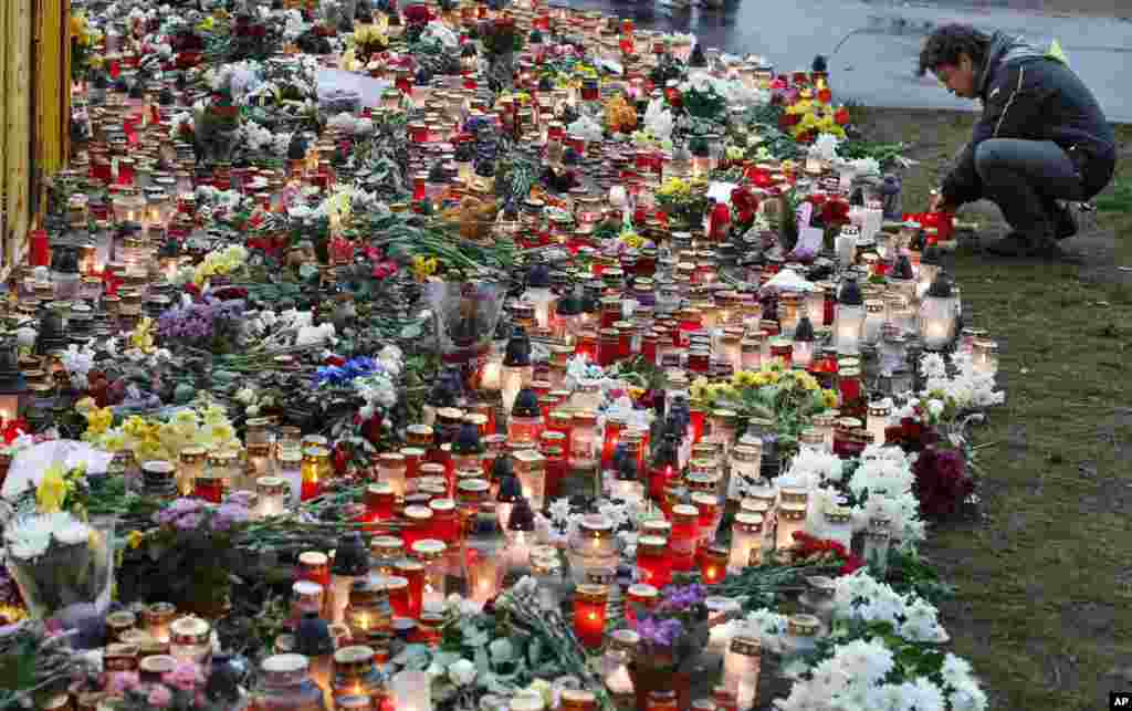 A man puts a lit candle in front of the Maxima supermarket after a section of its roof collapsed, in Riga, Latvia. More than 50 people were killed when the roof collapsed.