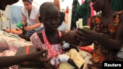 A South Sudanese nurse talks to a malnourished internally displaced orphan girl in the hospital run by Medecins Sans Frontieres (MSF) inside the camp for IDPs in Malakal, Upper Nile State, May 29, 2014. 