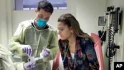 Ella Balasa, 26, of Richmond, Va., who has cystic fibrosis, and antibiotic-resistant bacteria lodged inside her lungs, watches as Yale University researcher Benjamin Chan pours a bacteriophagen for her to inhale, at the Winchester Chest Clinic, in Connecticut, Jan. 17, 2019.