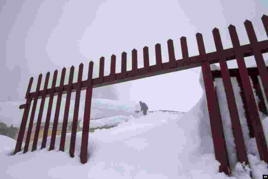 A Kashmiri man removes snow from a hotel premise in Gulmarg, about 55 kilometers (34 miles) northwest of Srinagar, Indian-controlled Kashmir. Authorities have issued avalanche warnings for many parts of the region, as the heavy snowfall has cut off roads, disrupted power and communication lines, and forced the evacuation of hundreds of residents.