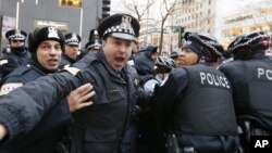 Polisi Chicago saat mengamankan seorang pemrotes di kawasan perbelanjaan "Magnificent Mile" (24/12) lalu. 