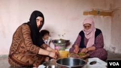 Ismahan, left, and her mother make traditional food using leaves plucked from trees, because they can not afford to buy them on May 20, 2020 in Istanbul. (Heather Murdock/VOA)