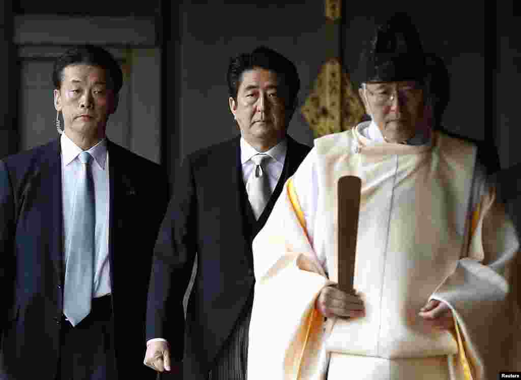 Japan&#39;s Prime Minister Shinzo Abe follows a Shinto priest as he visits Yasukuni Shrine in Tokyo, Dec. 26, 2013. 