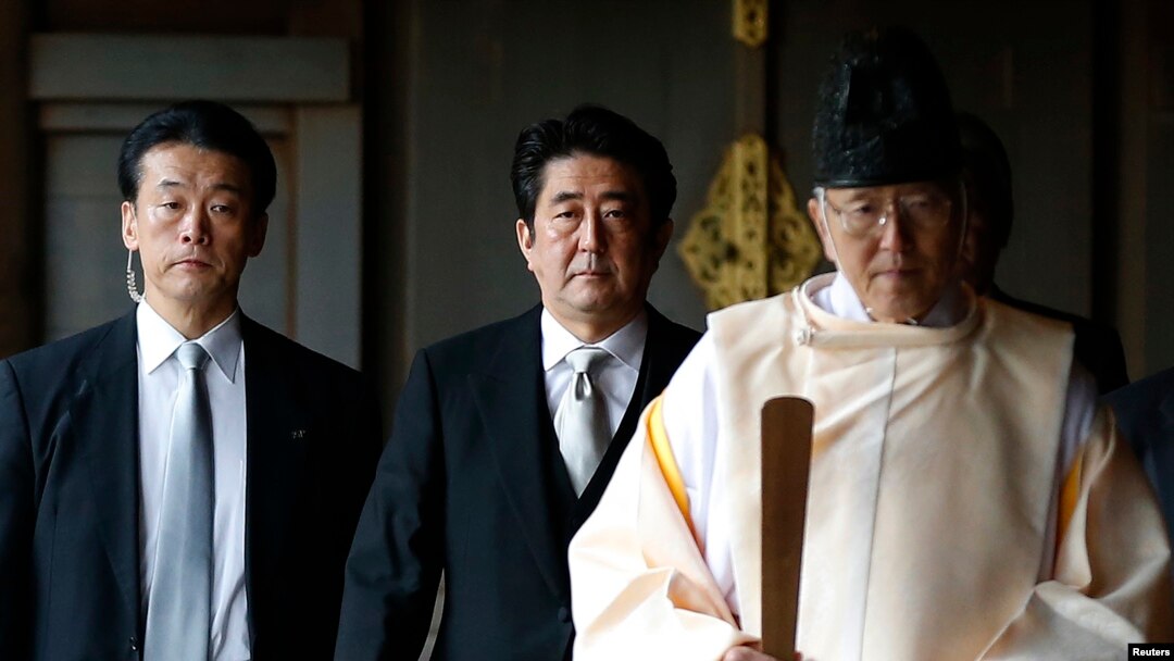PM Jepang Shinzo Abe (tengah) didampingi seorang Pendeta Shinto (kanan) mengunjungi kuil Yasukuni di Tokyo, Kamis (26/12).