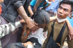 Protesters attend to a person wounded during demonstrations in Mandalay, a city in Myanmar, March 3, 2021. (Htet Aung Khant/VOA Burmese)
