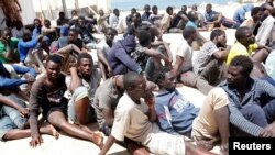 FILE - Illegal migrants sit at a naval base after they were rescued by Libyan coastguard in the coastal city of Tripoli, Libya, May 6, 2017. 