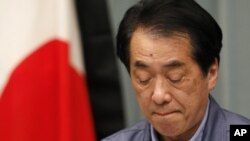 日本首相菅直人在记者会上，旁边是镶了黑边的日本国旗