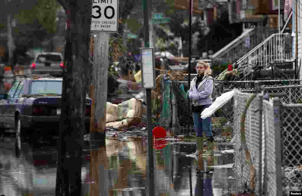 A woman stands alone in water in front of destroyed homes on Cedar Grove Avenue in a neighborhood where many houses were heavily damaged or completely destroyed by storm surge flooding from Hurricane Sandy on the south side of the Staten Island section of