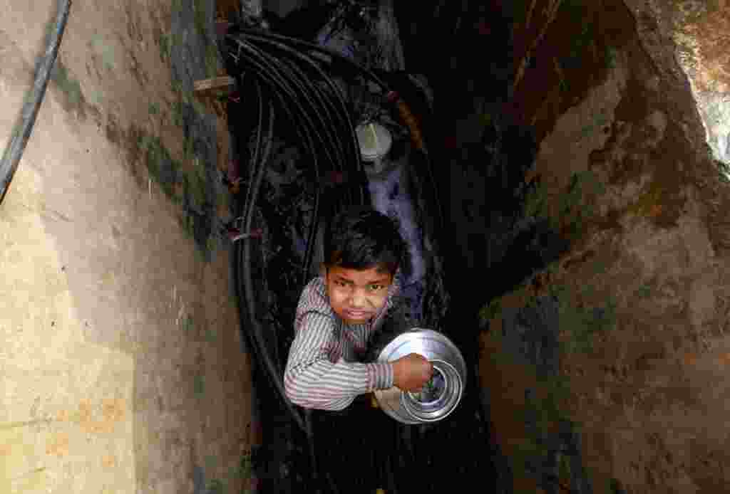 Un niño indio sostiene un recipiente tras recolectar agua en las afueras de un barrio de Bombay, India.