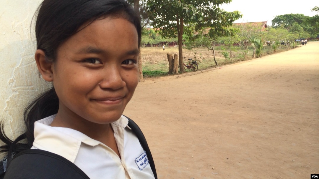 កុមារី​គុល ស្រីម៉ៅ ឈរ​នៅ​មុខ​សាលារៀន​របស់​នាង​ដែល​លោកស្រី Michelle Obama ភរិយា​ប្រធានាធិបតី​សហរដ្ឋ​អាមេរិក បាន​ទៅ​ធ្វើ​ទស្សនកិច្ច​នៅ​ខែមីនា​ឆ្នាំ២០១៥ ដើម្បី​ផ្សព្វផ្សាយ «គម្រោង​ផ្តល់​ឱកាស​ឲ្យ​ក្មេង​ស្រី​បាន​សិក្សា» «Let Girls Learn»។