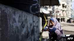 
A Palestinian girl fills bottles with water in Bureij in the central of Gaza Strip, on November 14, 2023, amid the ongoing battles between Israel and the Palestinian group Hamas. (Photo by MOHAMMED ABED / AFP)