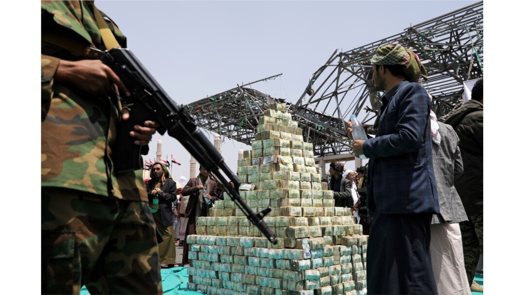 FILE - Houthi followers stand by bills of Yemeni currency during a ceremony held by Houthis to collect supplies for their fighters battling government forces in various front lines, in Sanaa, Yemen, Sept. 24, 2020.