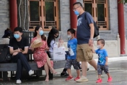 People wearing face masks to protect against the new coronavirus visit a shopping district in Beijing, July 19, 2020.