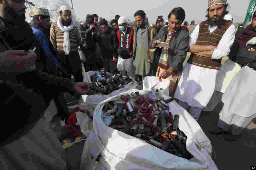 فیض آباد میں جاری دھرنے کے شرکا پولیس کی جانب سے پھنیکے گئے آنسو گیس کے شیل دکھا رہے ہیں