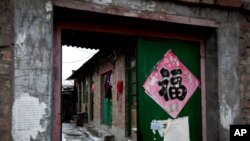 Clothes hang from a green entrance door of a single-story brick house, known as a "black jail" in Beijing, Feb. 5, 2013.