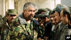 FILE - Rashid Dostum shakes hands with local residents in Shebergan, Afghanistan,, Dec. 27 , 2001. 
