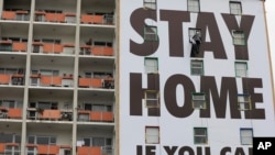 A billboard is installed on an apartment building in Cape Town, South Africa, March 25, 2020, calling on people to stay indoors to fight the spread of the new coronavirus. 