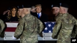 President Donald Trump and first lady Melania Trump look on as a U.S. Army carry team moves a transfer case containing the remains of Chief Warrant Officer 2 David C. Knadle, of Tarrant, Texas, Nov. 21, 2019, in Dover Air Force Base, Del.
