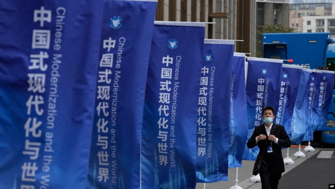 一名男子走過上海街頭插滿的宣傳旗幟：「中國式現代化與世界」。 （2023年4月21日）