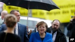 German Chancellor Angela Merkel, center, arrives for exploratory talks about a new German government between her Christian Unions block and the Social Democratic Party at the SPD headquarters in Berlin, Jan. 11, 2018.