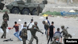 A Spanish legionnaire hits a Moroccan citizen at El Tarajal beach, near the fence between the Spanish-Moroccan border, after thousands of migrants swam across this border during last days, in Ceuta, Spain, May 18, 2021. 