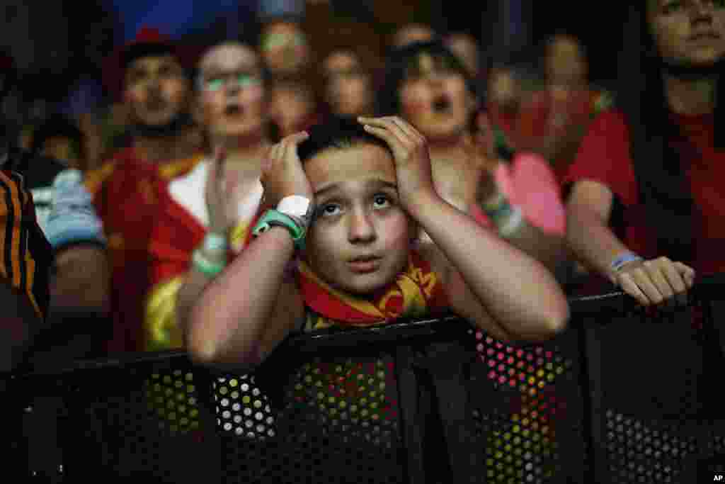 A Spanish soccer fan holds her head as she watches, on a giant display, the World Cup soccer match between Spain and Chile, in Madrid, Spain, June 18, 2014.