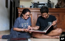 Ni Luh Erniati sits with her son, Made, going through family photo albums which show her late husband and his late father, Gede Badrawan, in Bali, Indonesia, Apr. 25, 2019. Gede was one of 202 people killed in the 2002 Bali bombings.