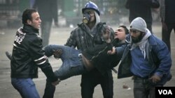 Manifestantes cargan a un colega herido durante choques cerca de la Plaza Tahrir.