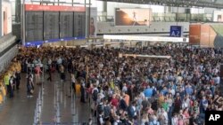 Passengers wait in a hall of Terminal 1 of the Frankfurt Airport, in Frankfurt Germany, Aug. 7, 2018 after parts of a terminal were evacuated over concerns that a security barrier was breached.