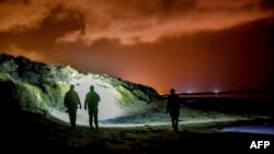 FILE - French gendarmes patrol on the beach of Oye-Plage, near Calais, northern France, Jan. 9, 2019 as they try to intercept migrants attempting to cross the Channel. British authorities intercepted 74 people on eight vessels trying to cross the English Channel on June 1, 2019.